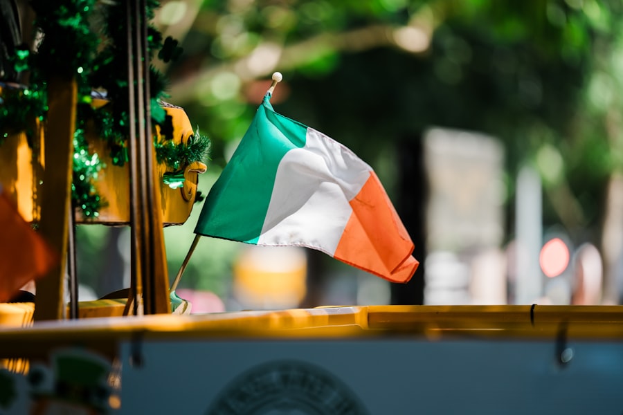 An irish flag waves gently outdoors with blurred background.